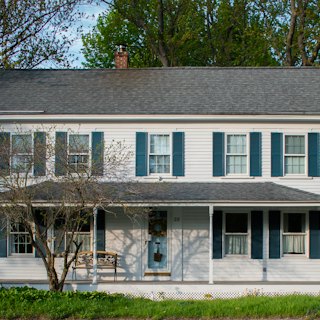A white house with blue shutters and a front porch